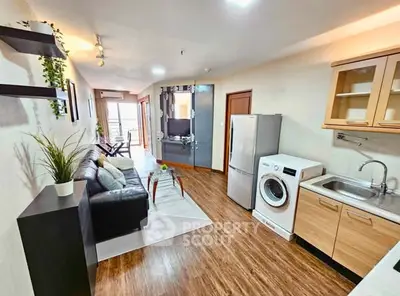 Modern open-plan living room with kitchen, featuring sleek appliances and stylish decor.