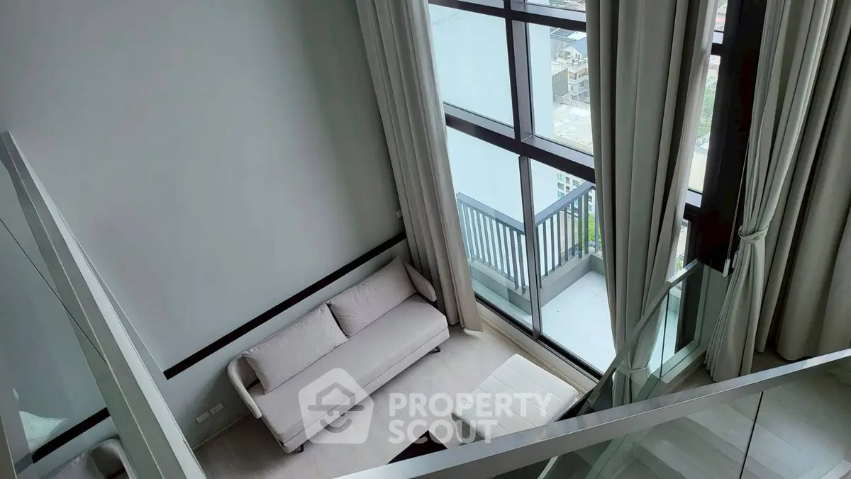 Modern loft apartment with floor-to-ceiling windows and cozy balcony offering stunning city views.