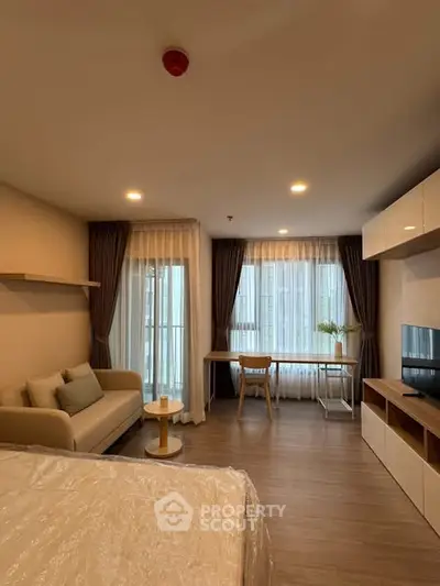 Modern living room with cozy sofa and elegant decor, featuring large windows and stylish furniture.