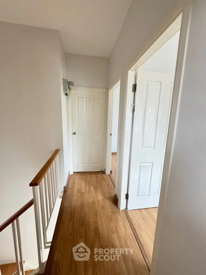 Bright hallway with wooden flooring and white doors in a modern home.