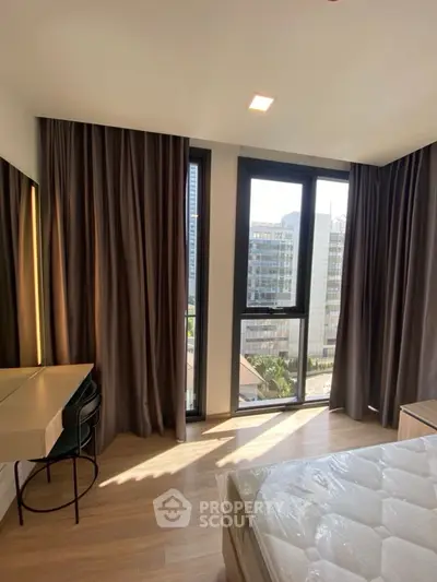 Modern bedroom with large windows and natural light in urban setting.