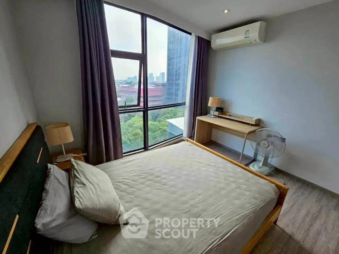 Modern bedroom with large window and city view, featuring air conditioning and minimalist decor.