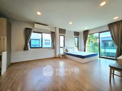 Spacious bedroom with large windows and modern decor in a bright apartment.