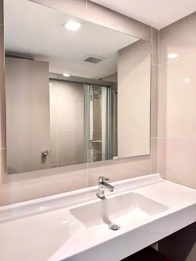 Modern bathroom with sleek sink and large mirror in contemporary apartment.