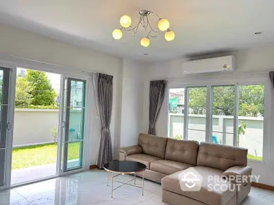 Spacious living room with modern sofa and garden view, perfect for family gatherings.