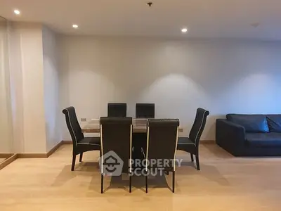 Spacious dining area with elegant black chairs and a cozy sofa, perfect for modern living.