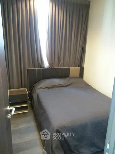 Cozy bedroom with dark curtains and modern furnishings, perfect for restful nights.