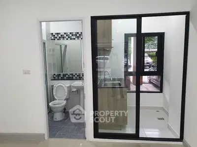 Modern apartment with compact bathroom and kitchen area, featuring sleek design and efficient layout.