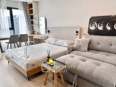 Modern studio apartment with stylish decor, featuring a cozy bed, chic sofa, and a functional workspace.