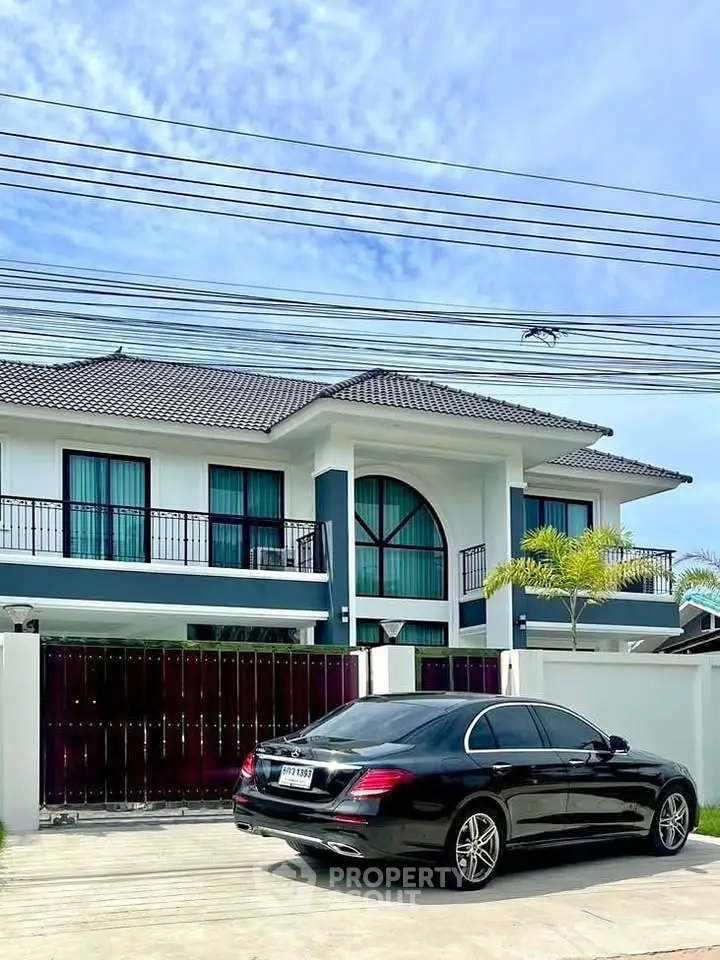 Luxurious modern two-story house with sleek black car parked in driveway, showcasing elegant architecture.
