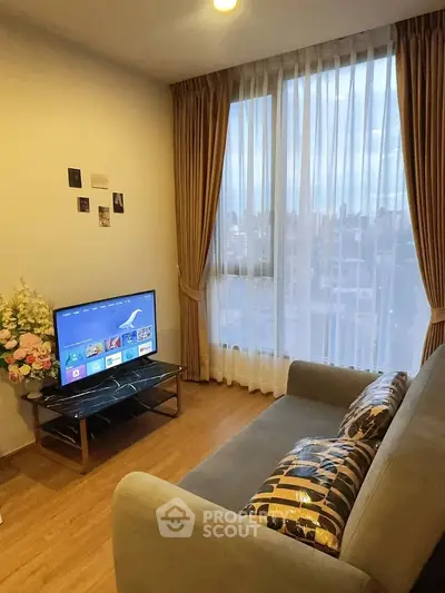 Cozy living room with city view, featuring a modern sofa and entertainment setup.