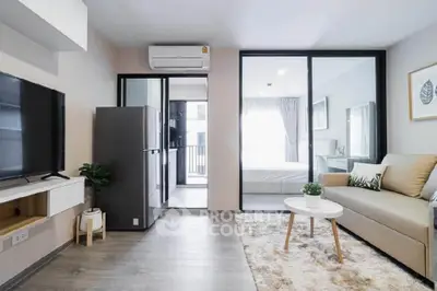 Modern open-plan living room with cozy sofa, TV, and sleek kitchen area in stylish apartment.