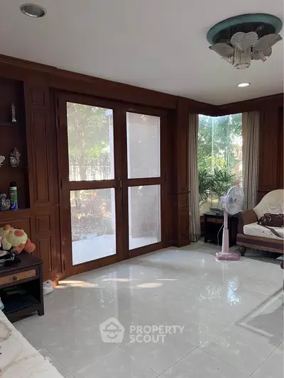 Spacious living room with wooden accents and large windows overlooking a garden.