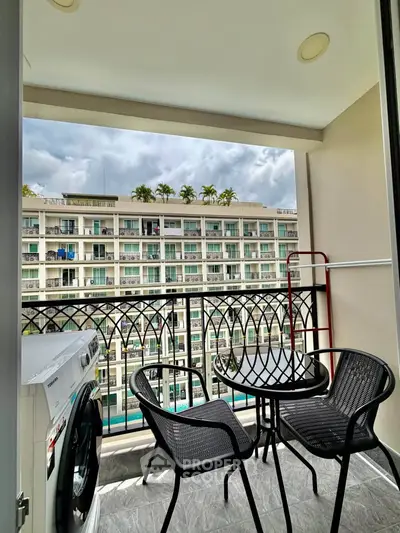 Charming balcony with outdoor seating and washing machine, overlooking modern apartment complex.