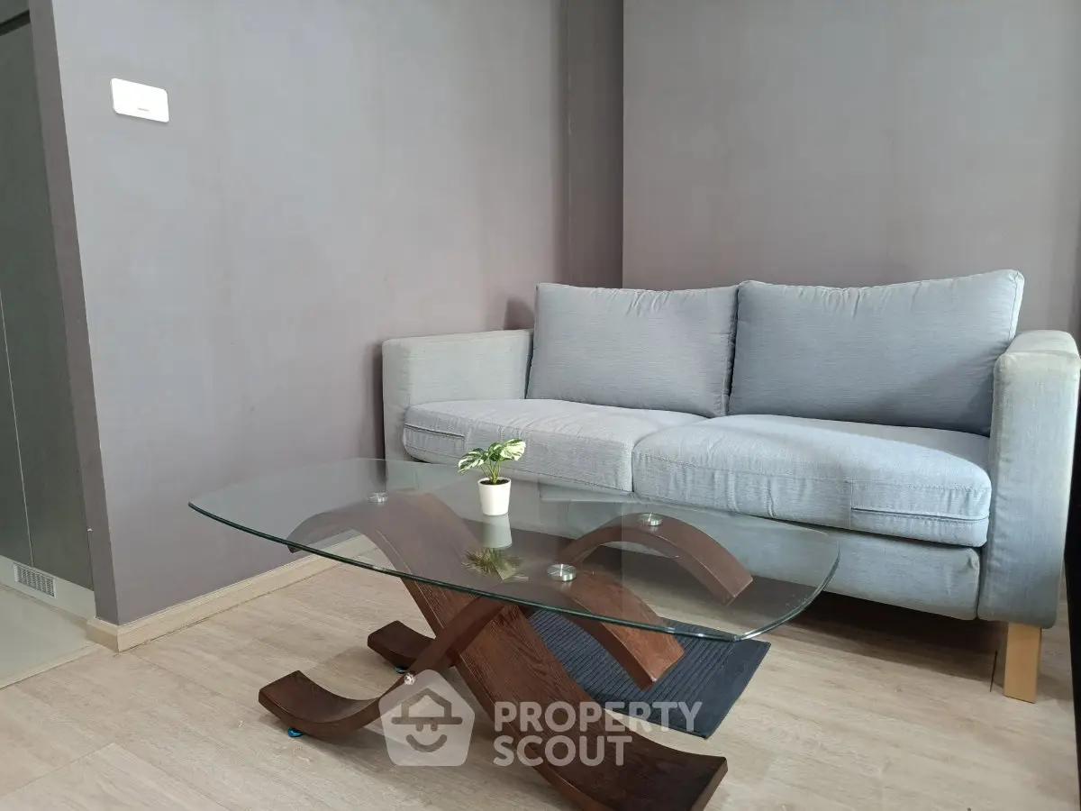 Modern living room with stylish glass coffee table and cozy gray sofa, perfect for relaxation.