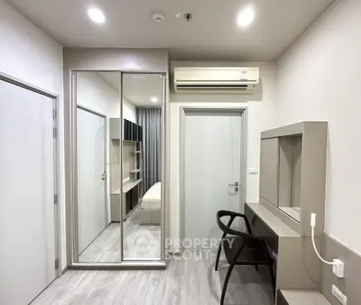 Modern bedroom with mirrored closet and sleek workspace in minimalist design.