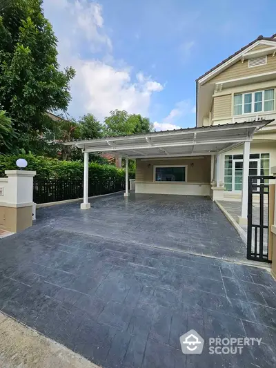 Spacious driveway and entrance of a modern house with covered parking area.