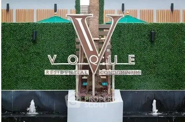 Elegant entrance sign of Vogue Residential Condominium with lush greenery and water features.