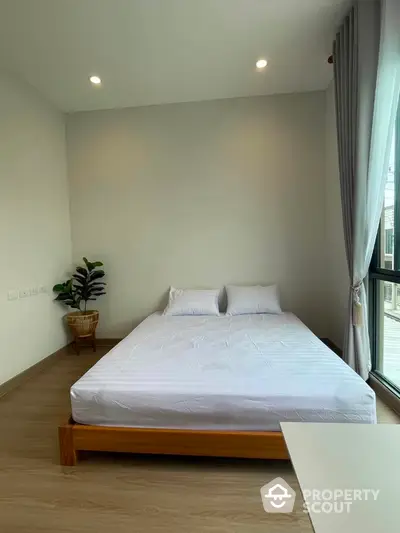 Modern minimalist bedroom with large window and natural light