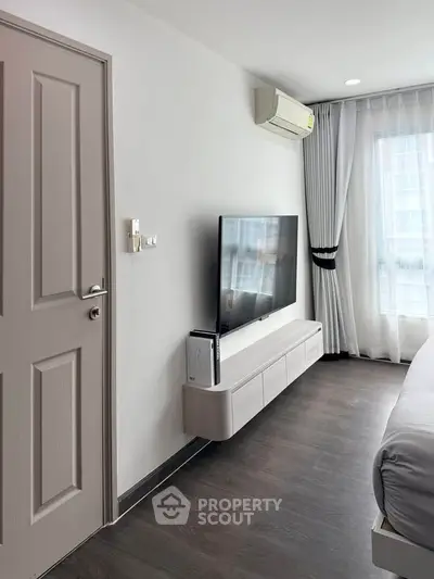 Modern bedroom with sleek TV setup and elegant curtains