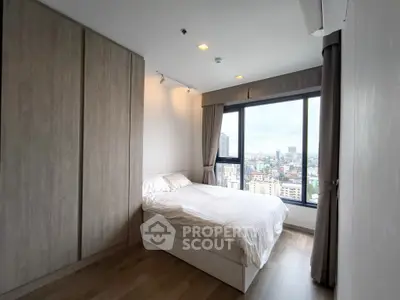 Modern bedroom with city view and large window, featuring sleek wooden wardrobe.