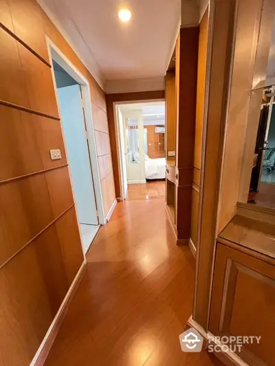 Spacious hallway with wooden flooring leading to a cozy bedroom in a modern apartment.