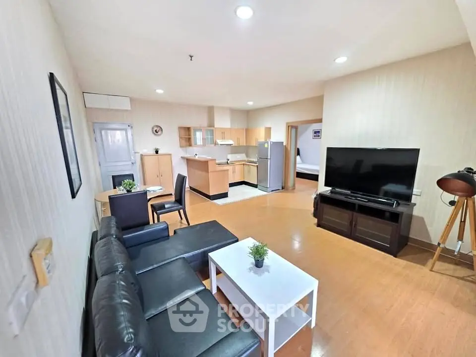 Spacious living room with modern furniture and open kitchen layout in a cozy apartment.