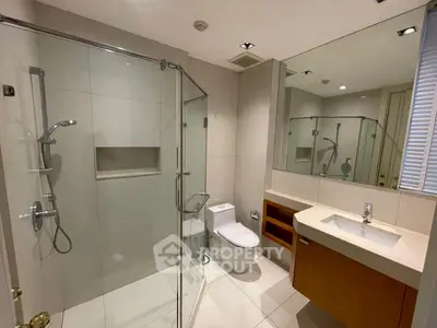 Modern bathroom with glass shower and sleek vanity in luxury apartment.