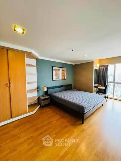 Spacious bedroom with modern decor and city view, featuring wooden flooring and ample natural light.