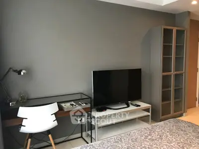 Modern bedroom with sleek desk, TV, and stylish storage cabinet.