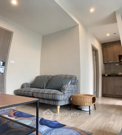 Cozy living room with stylish sofa and modern kitchen in open layout apartment.