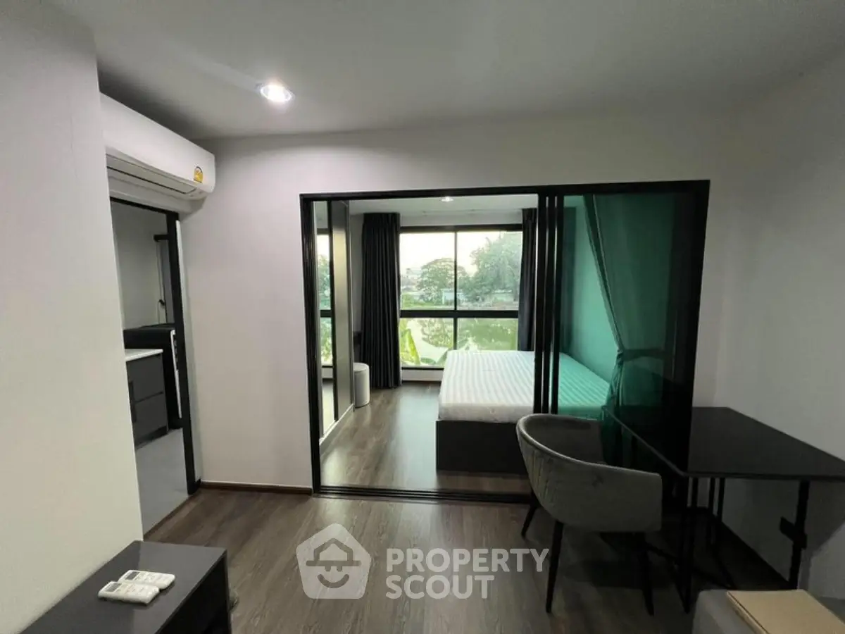 Modern studio apartment with glass partition, featuring a cozy bedroom and workspace.