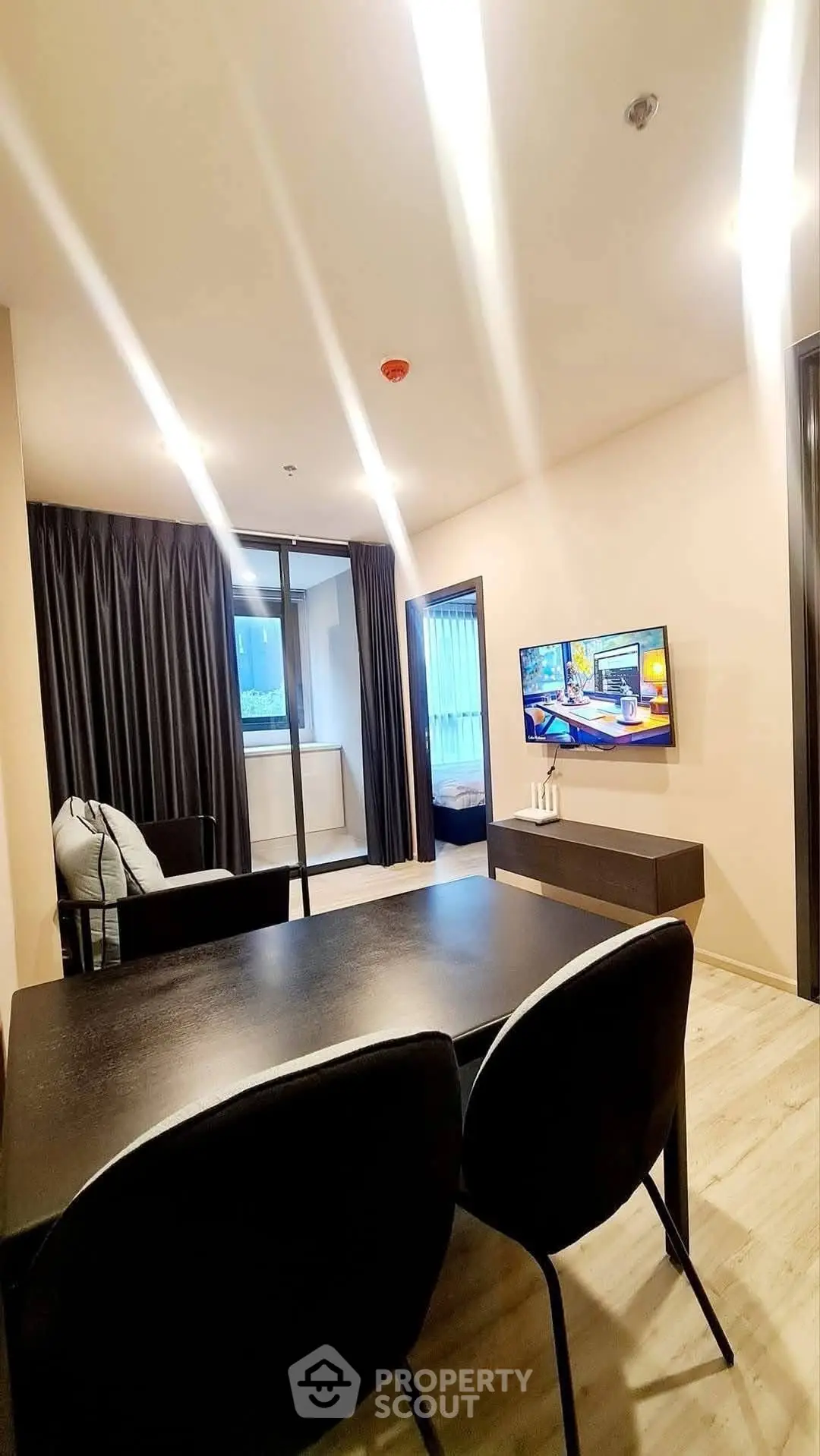 Modern living room with sleek furniture and wall-mounted TV, featuring a view of the balcony.