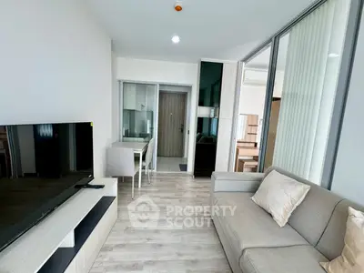 Modern living room with sleek furniture and open layout, featuring a large TV and cozy sofa.