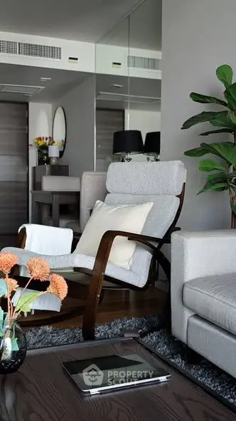 Modern living room with stylish furniture and elegant decor, featuring a cozy armchair and lush indoor plant.