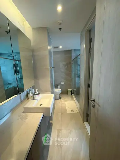 Modern bathroom with sleek design, featuring a spacious shower and elegant fixtures.