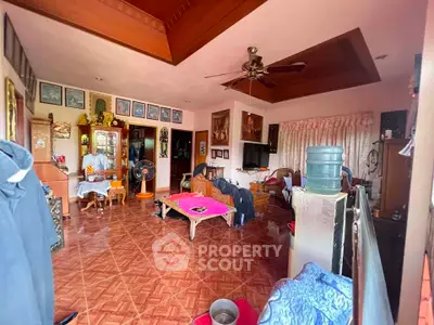 Spacious living room with elegant wooden ceiling and tiled floor, featuring cozy seating and decorative elements.
