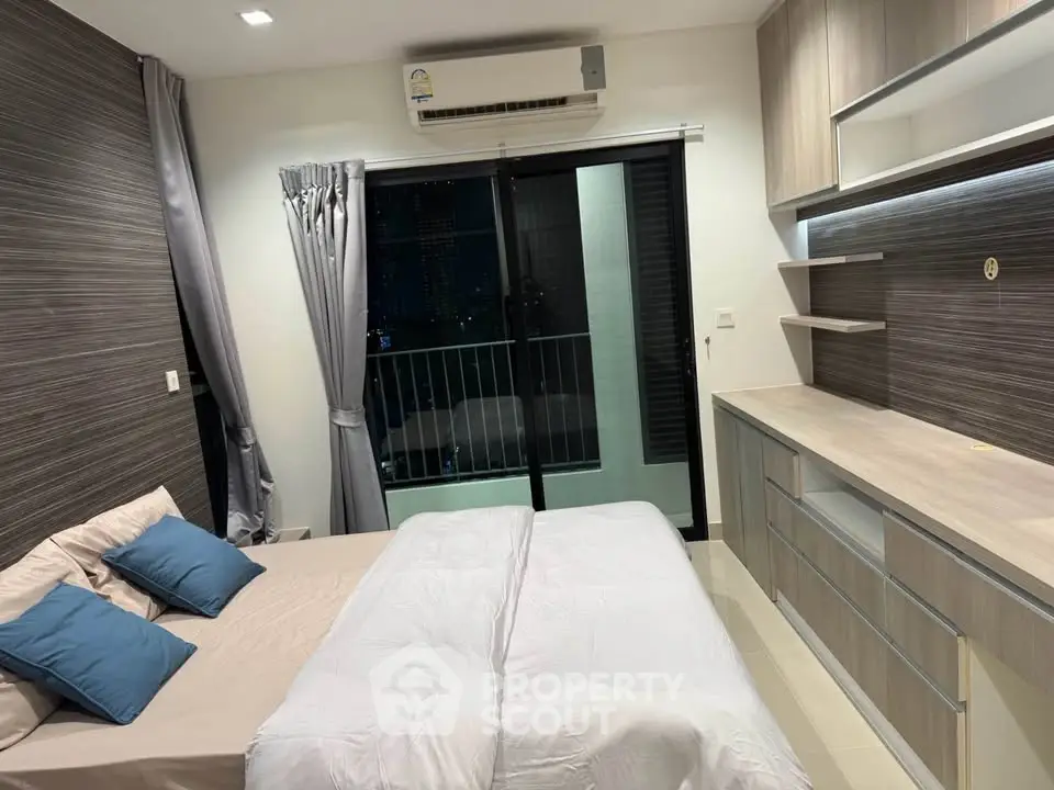 Modern bedroom with balcony view, featuring sleek cabinetry and air conditioning for ultimate comfort.