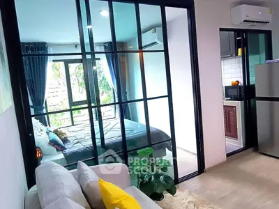 Modern apartment with glass partition, cozy living area, and compact kitchen.