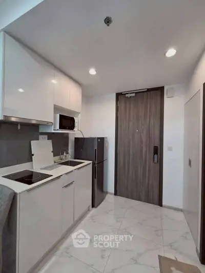 Modern kitchen with sleek white cabinets and appliances in a stylish apartment.