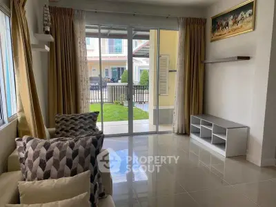 Bright living room with large windows and garden view, perfect for relaxation and entertaining.