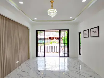 Spacious modern living room with marble flooring and elegant chandelier, featuring large windows with garden view.