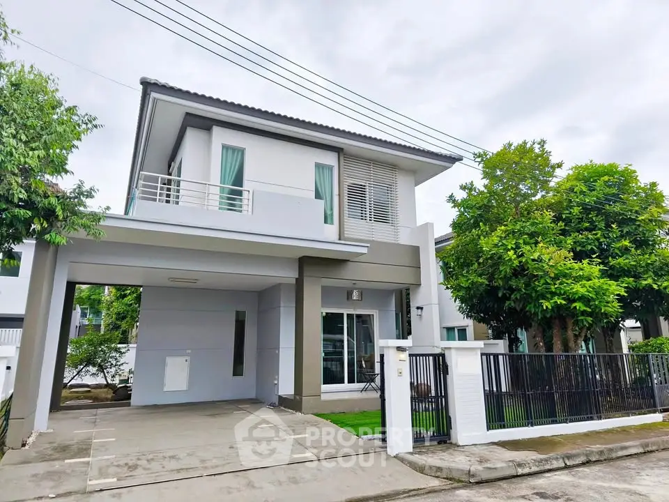 Modern two-story house with carport and lush greenery in a suburban neighborhood.