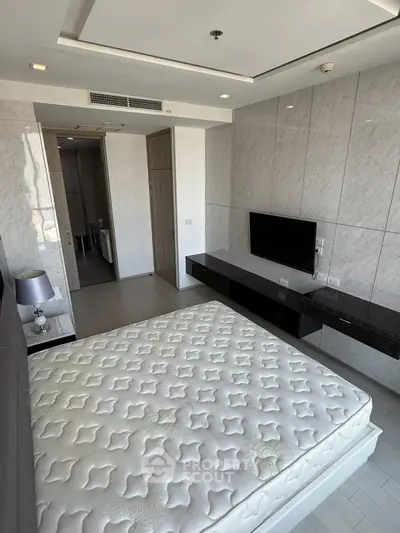 Modern bedroom with sleek design, featuring a wall-mounted TV and stylish decor, perfect for urban living.