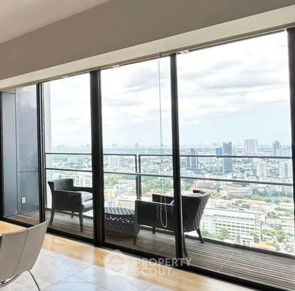 Stunning high-rise apartment with floor-to-ceiling windows offering breathtaking city views from a spacious balcony.