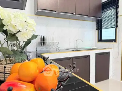 Modern kitchen with sleek cabinets and marble backsplash, featuring a fruit basket centerpiece.