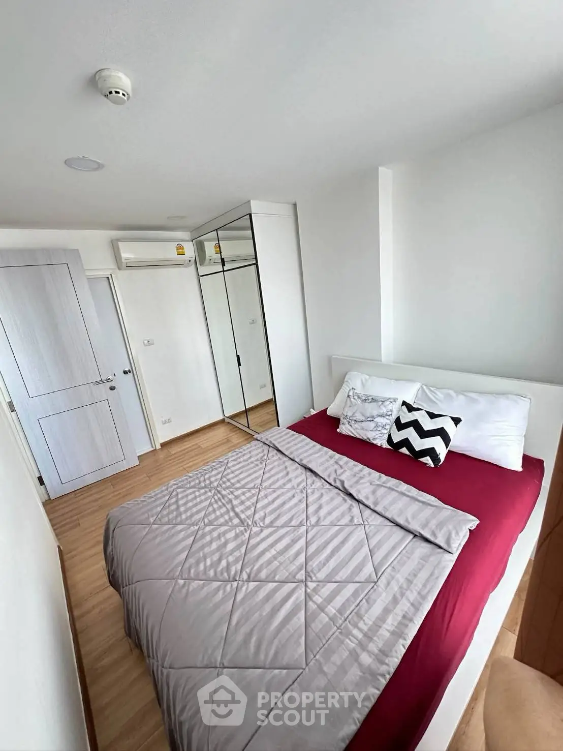 Modern bedroom with stylish decor and mirrored wardrobe in a cozy apartment.