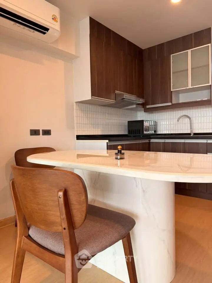Modern kitchen with sleek wooden cabinets and marble island in a stylish apartment.