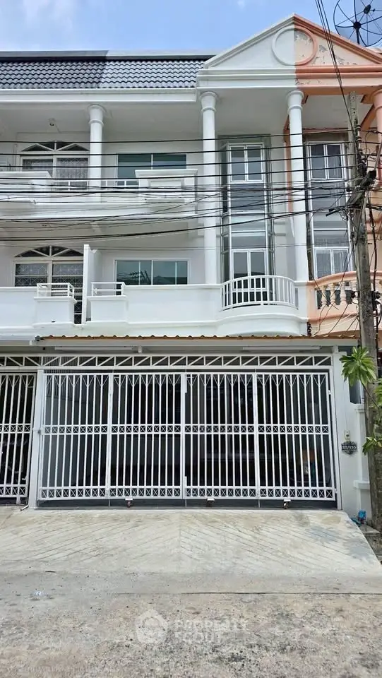 Elegant multi-story townhouse with modern facade and gated entrance in urban setting.
