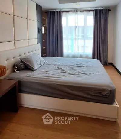 Modern bedroom with stylish decor and large window for natural light.